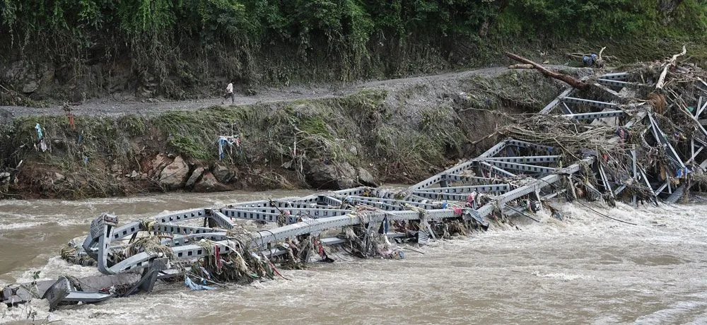 A road bridge over the Trishuli dropped into the river, its deck broken and the approach washed away.
