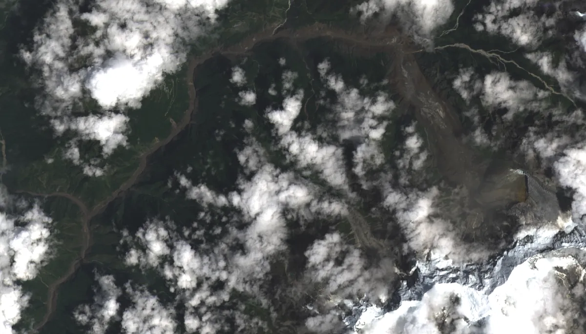 Satellite view of the same valleys on the day of the flood, a wide brown scour running down the river