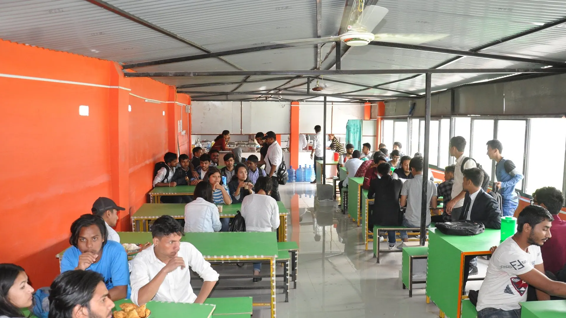 The ICE campus canteen mid-service, students at the tables along the window wall