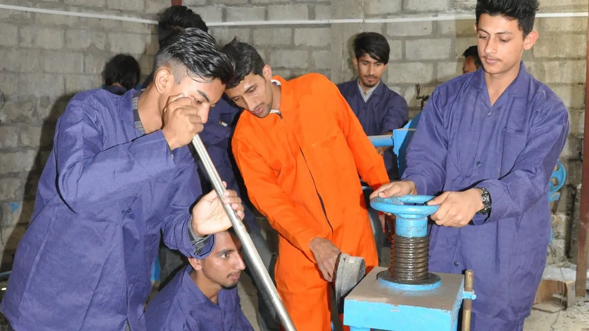Students in coveralls loading a specimen into the compression testing frame