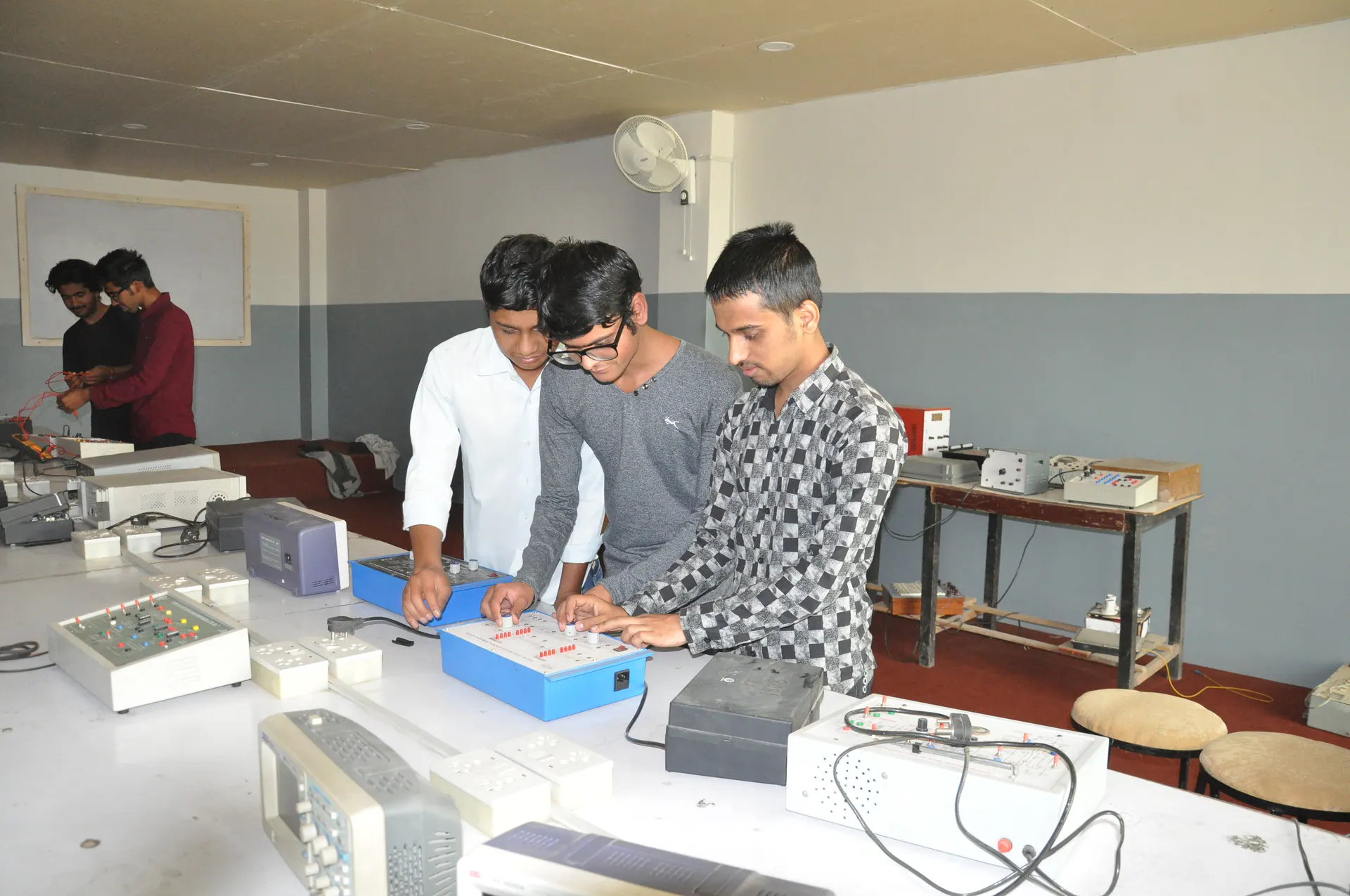 Students and an instructor working together at an electronics laboratory bench
