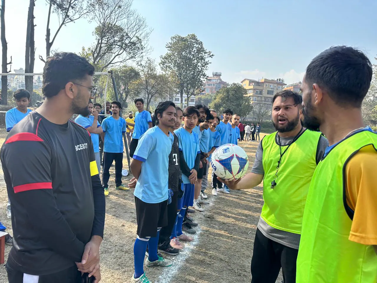 Students gathering around a football during an outdoor sports session
