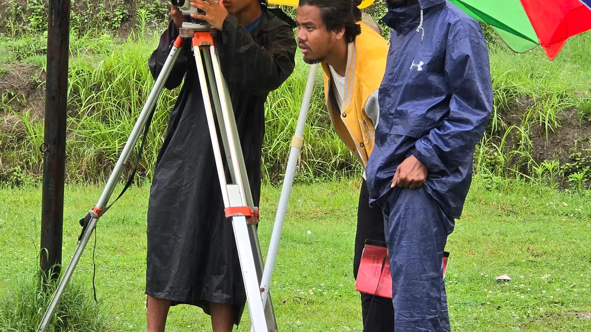 Civil Engineering students carrying on with survey fieldwork in the wet