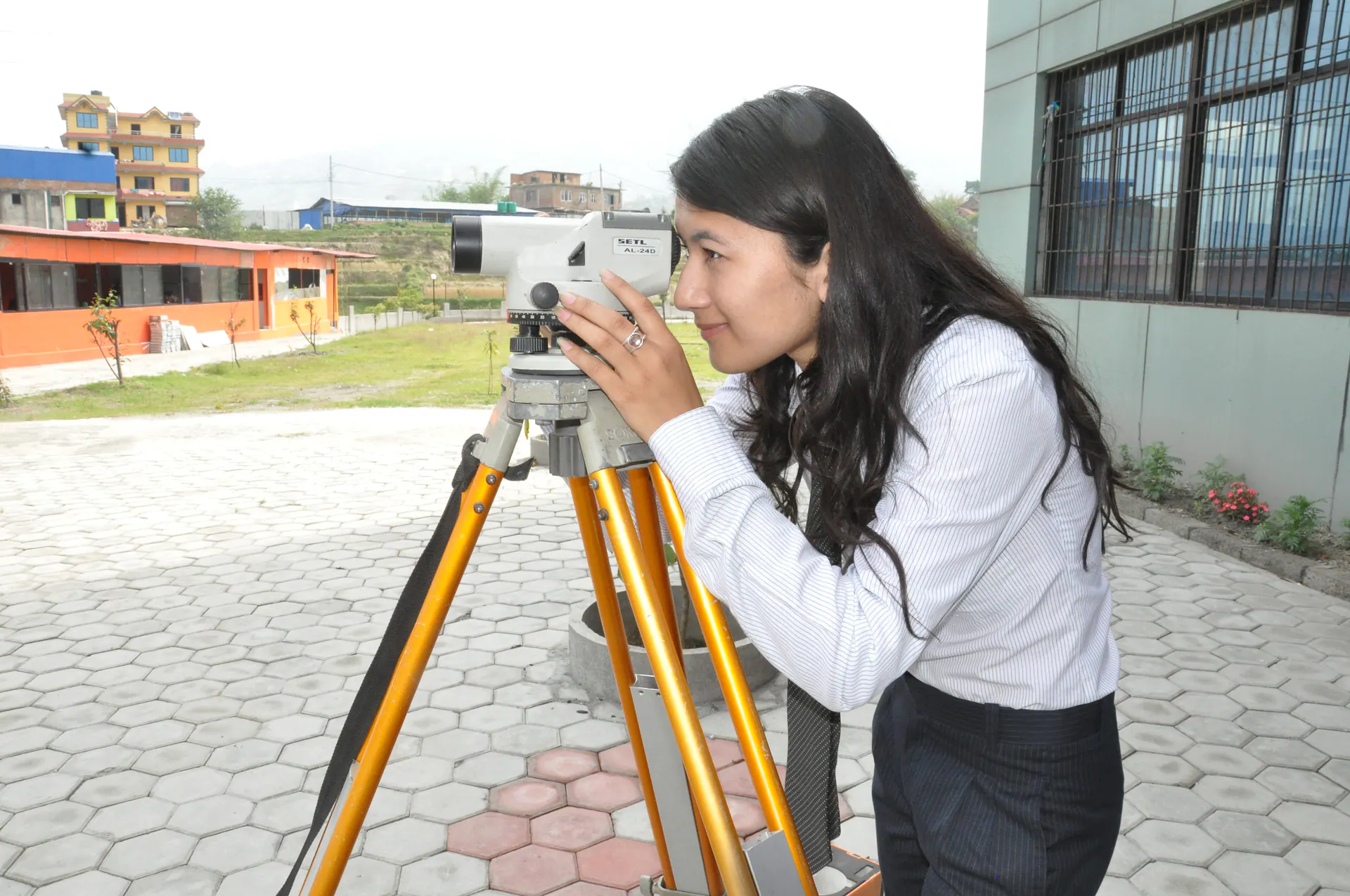 An engineering student consulting notes during an outdoor survey practical